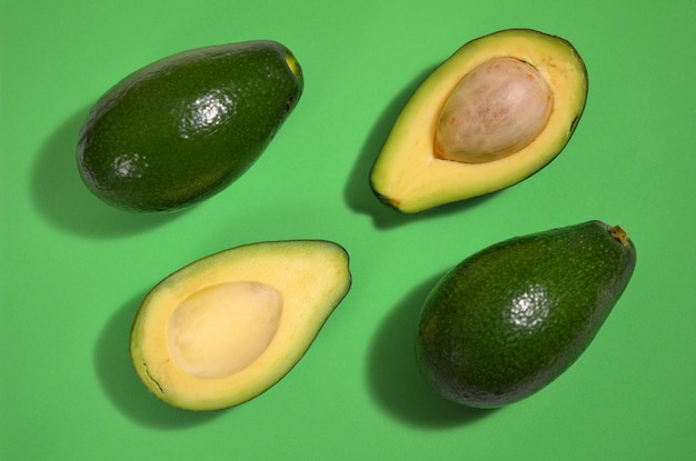 Imagen brillante corte de fruta de aguacate fresco sobre fondo verde, endecha plana