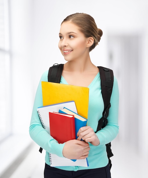 Imagen brillante de estudiante sonriente con libros y mochila.