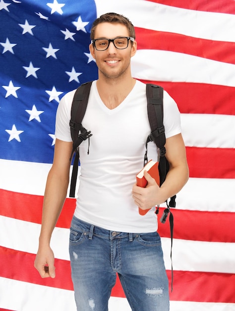 Foto imagen brillante de estudiante viajero con mochila y libro sobre bandera americana
