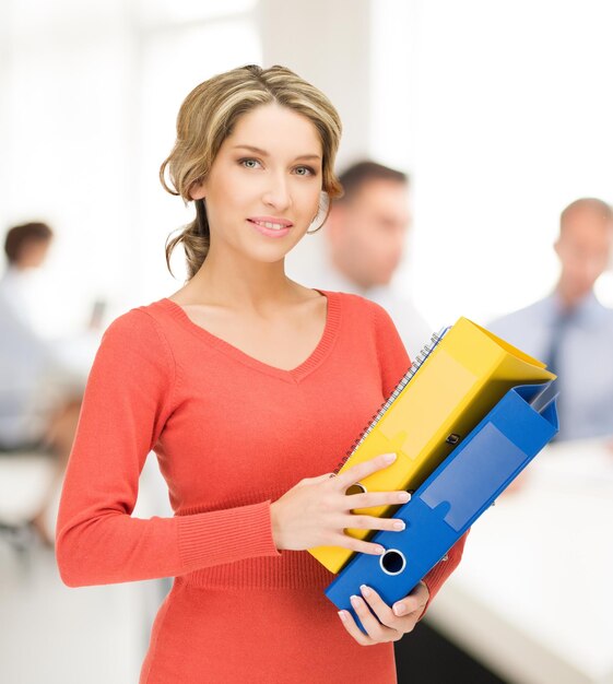 Imagen brillante de hermosa mujer con carpetas en Office