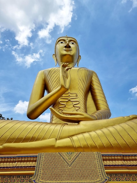 Imagen de Buda en postura de bendición sobre el fondo del cielo azul en el templo Wat Phrathat Wayo, Tailandia