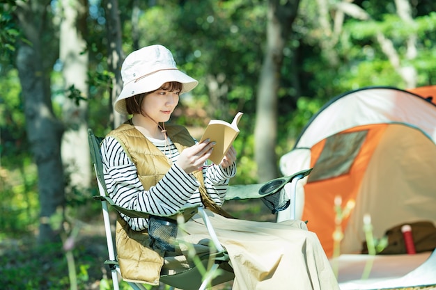 Imagen de campamento en solitario: mujer joven leyendo un libro