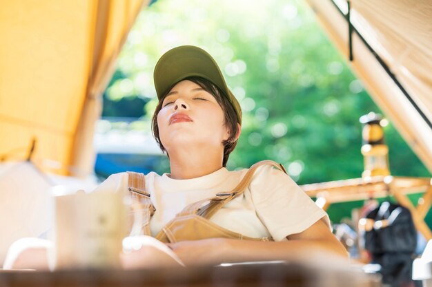 Imagen de campamento en solitario - mujer joven tomando una siesta frente a una carpa