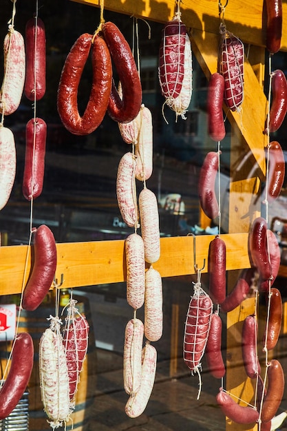 Foto imagen de la carnicería con salchichas frescas y coloridas colgando en la ventana