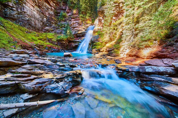 Imagen de la cascada escondida en el cañón con agua azul vibrante y rocas de río