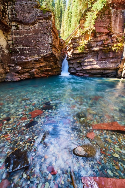 Imagen de la cascada que atraviesa escarpados acantilados en agua azul prístina con rocas de colores