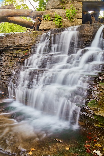 Imagen de cascada serena y tranquila con hojas de otoño y ruinas