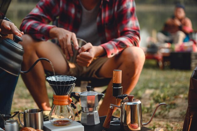 Imagen de cerca del estilo de campamento del hombre que hace café por goteo en el bosque de la naturaleza Le gusta viajar e ir de campamento
