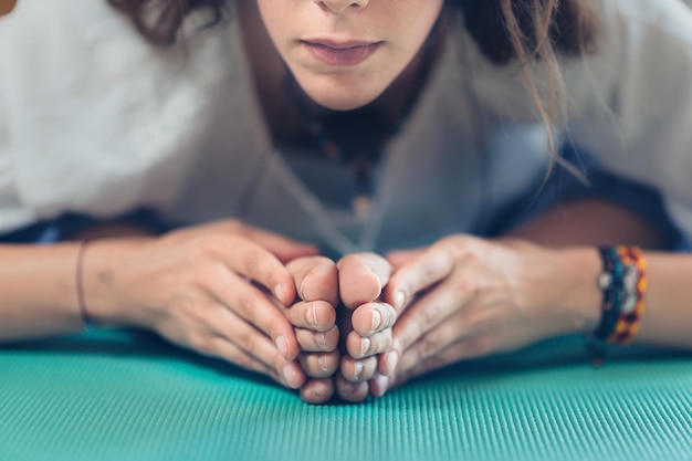 Imagen de cerca de una hermosa joven haciendo ejercicio de yoga en un estudio de yoga sentada en una estera de yoga turquesa