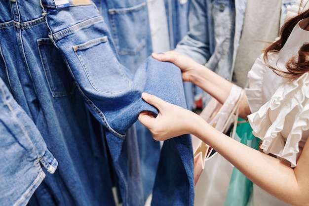 Imagen cercana de mujer joven eligiendo jeans en grandes almacenes