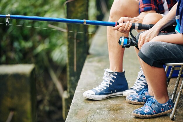 Imagen cercana de padre e hijo pescando con spinning moderno, concepto de paternidad