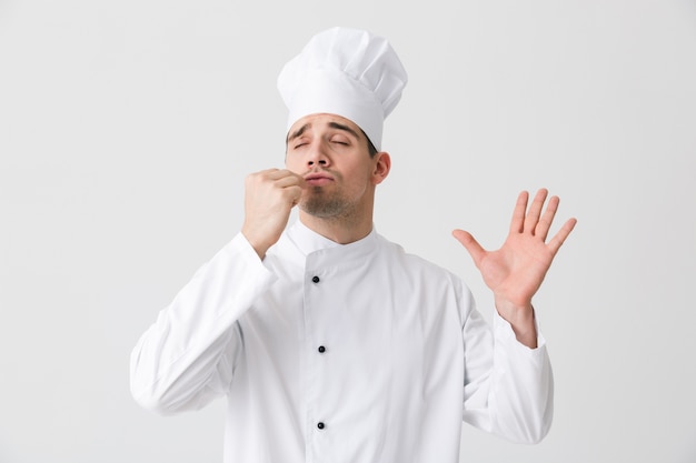 Imagen de chef joven guapo en interiores aislado sobre fondo de pared blanca.