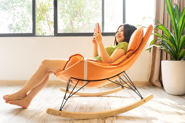 Imagen de una chica asiática relajándose en una silla en su casa
