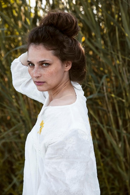 Imagen de una chica rizada con motas vestida con un vestido blanco aislado en un fondo de campo