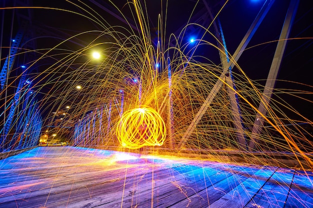 Imagen de chispas amarillas volando sobre un puente en la noche con una esfera interior de múltiples anillos de luz amarilla