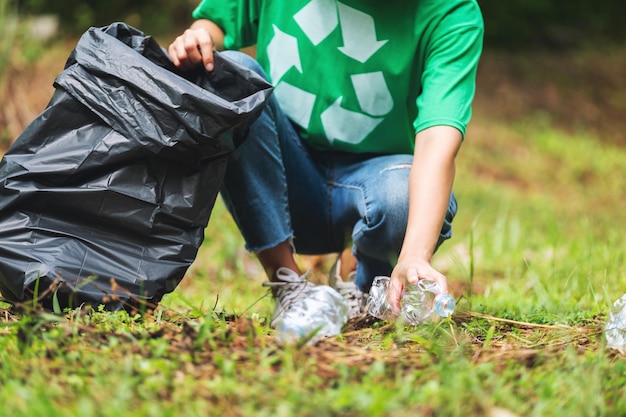 Imagen de cierre de una activista recogiendo botellas de plástico de basura en una bolsa de plástico en el parque para el concepto de reciclaje