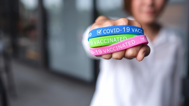 Foto imagen de cierre de una mujer que usa y muestra una colorida pulsera de vacunación covid19 para el concepto de atención médica