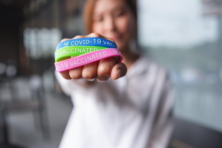 Foto imagen de cierre de una mujer que usa y muestra una colorida pulsera de vacunación covid19 para el concepto de atención médica