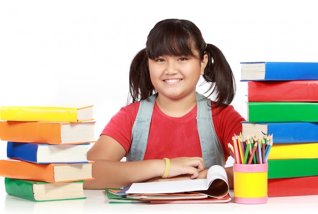 Imagen de colegiala sonriendo con el montón de libros contra blanco