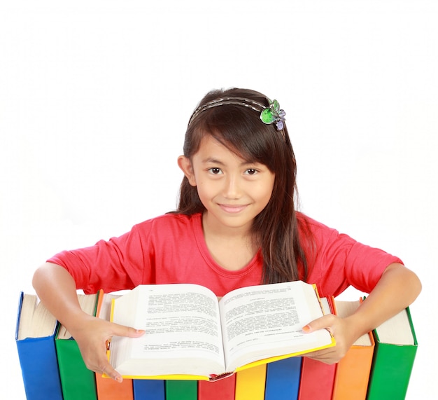 Foto imagen de una colegiala sonriendo con sus libros y leyendo uno de ellos