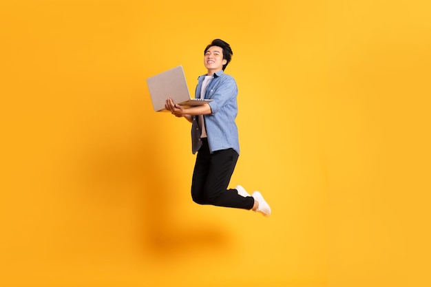 Imagen completa del cuerpo de un hombre asiático posando sobre un fondo amarillo