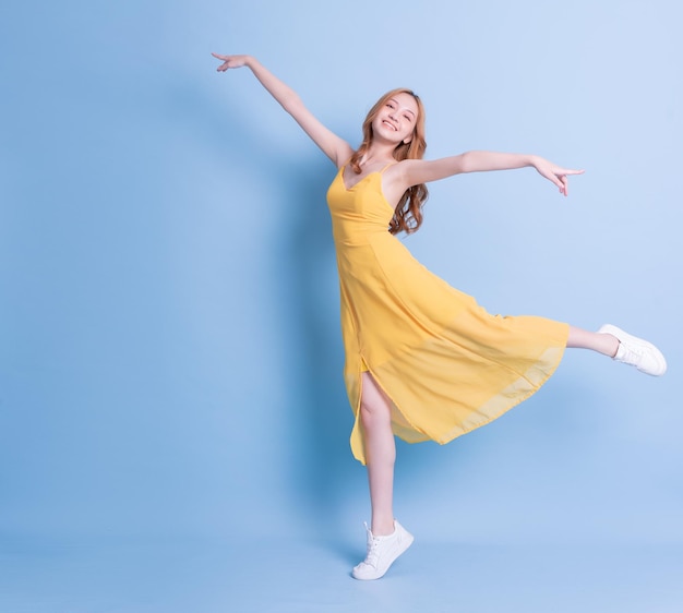 Imagen completa de una joven asiática con un vestido amarillo de fondo azul