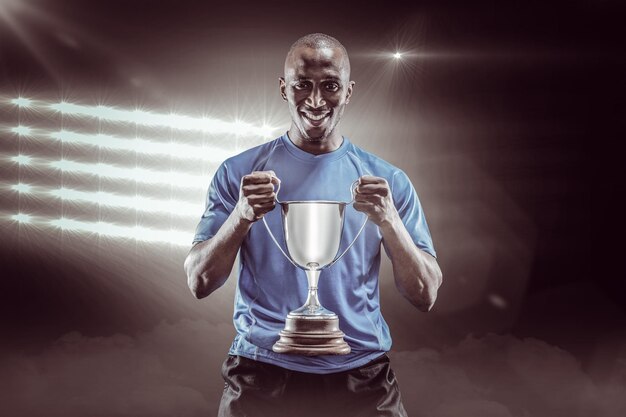 Imagen compuesta 3D de retrato de feliz deportista sosteniendo trofeo