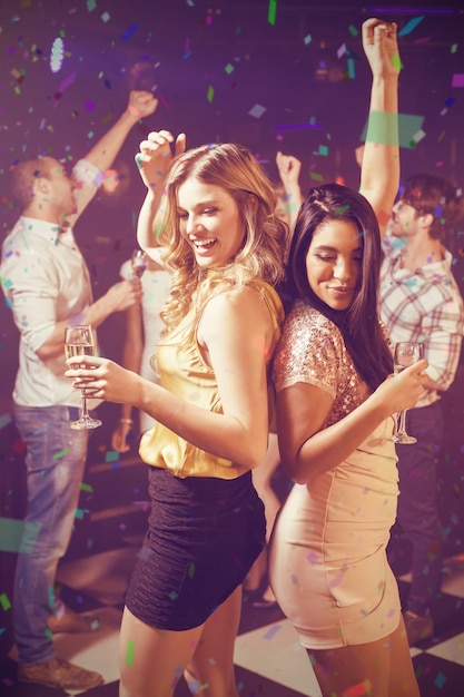 Imagen compuesta de amigos felices bailando mientras toma una copa