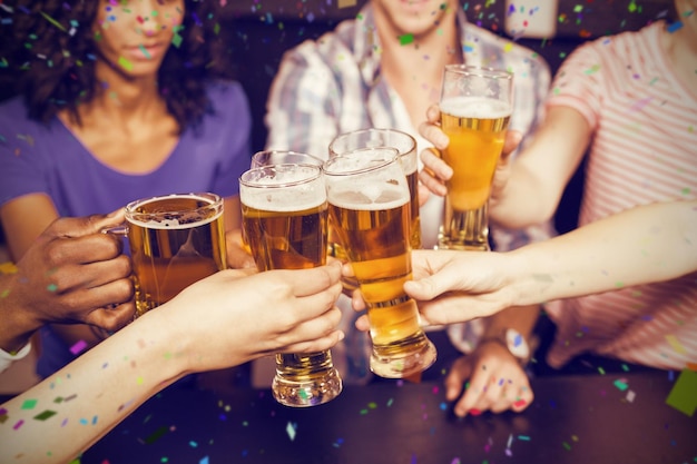 Imagen compuesta de amigos felices bebiendo cerveza y brindando