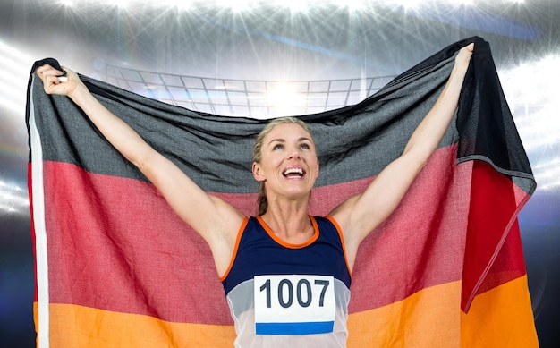 Imagen compuesta de atleta posando con bandera alemana tras la victoria