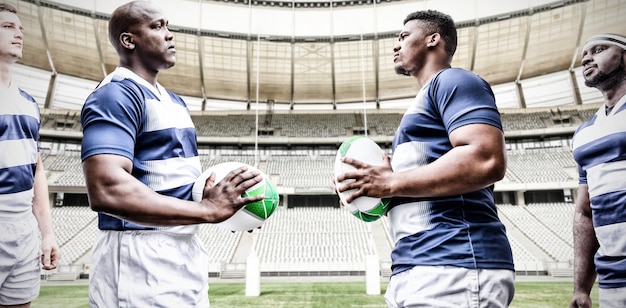 Imagen compuesta digital del equipo de jugadores de rugby uno frente al otro mientras sostiene la pelota de rugby en el deporte