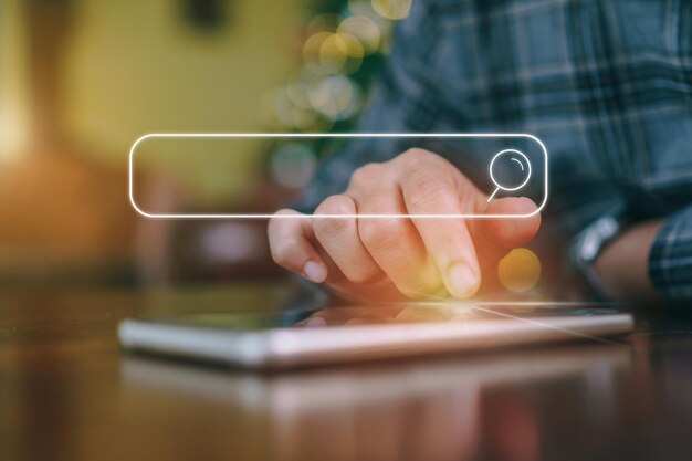 Imagen compuesta digital de un hombre usando un teléfono móvil con un icono de búsqueda en la mesa