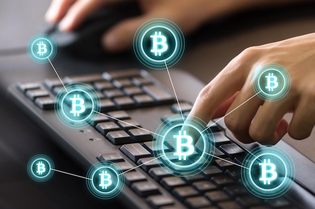Imagen compuesta digital de manos recortadas usando el teclado de la computadora por iconos de bitcoin