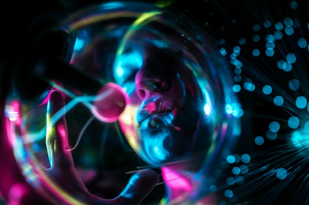 Imagen compuesta digital de una mujer y una bola de plasma con fibra óptica