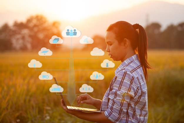 Imagen compuesta digital de una mujer joven usando una computadora portátil por plantas con iconos