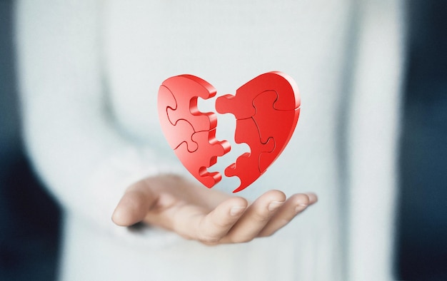 Imagen compuesta digital de una mujer sosteniendo un rompecabezas en forma de corazón