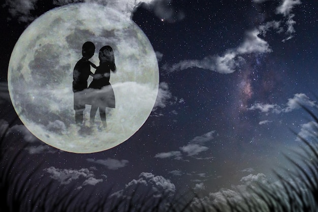 Imagen compuesta digital de una pareja de siluetas en la luna contra el cielo nocturno