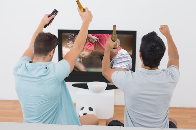 Imagen compuesta de emocionados aficionados al fútbol viendo la televisión