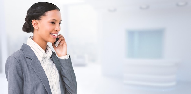 Imagen compuesta de empresaria sonriente a través de teléfono móvil