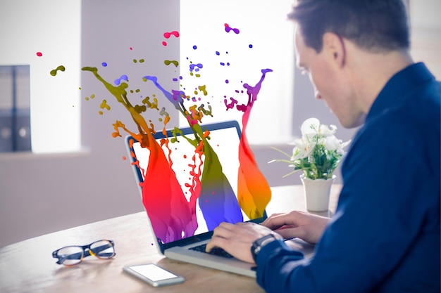 Imagen compuesta del empresario utilizando el portátil en la mesa en la oficina