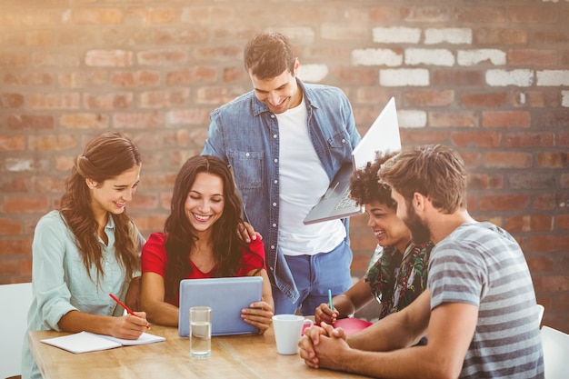 Imagen compuesta del equipo empresarial creativo reunido alrededor de una tableta