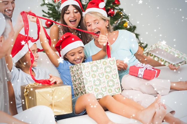 Imagen compuesta de familia feliz en Navidad abriendo regalos juntos