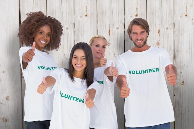 Imagen compuesta de feliz grupo de voluntarios dando Thumbs up