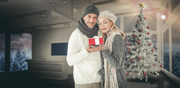 Imagen compuesta de feliz pareja de invierno con regalo