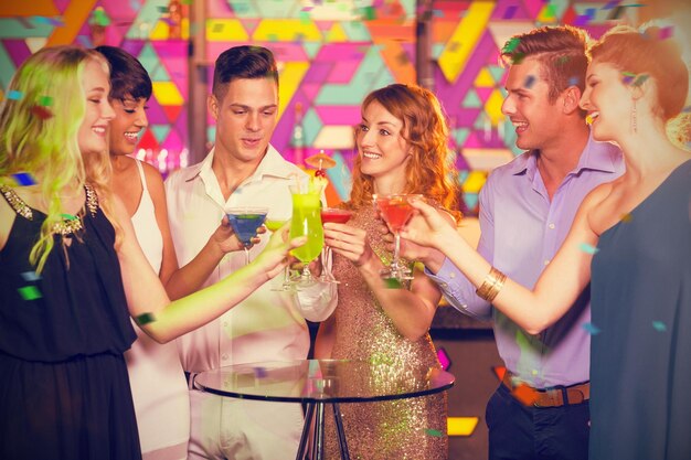 Imagen compuesta de un grupo de amigos brindando una copa de cóctel en el bar