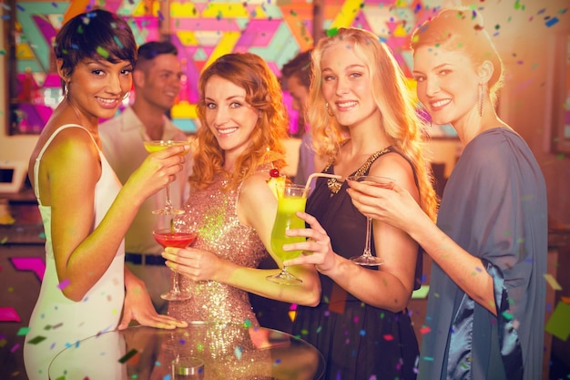 Imagen compuesta de un grupo de amigos con una copa de cóctel en el bar