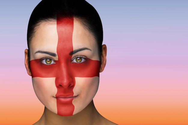 Imagen compuesta de hermosa morena en pintura facial de Inglaterra contra el hermoso cielo naranja y azul