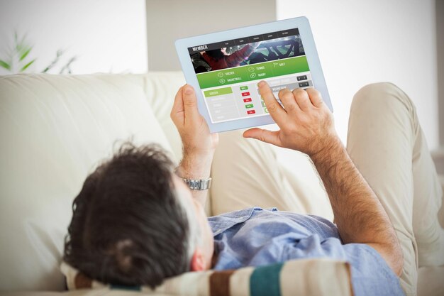 Imagen compuesta del hombre tendido en un sofá con un tablet pc