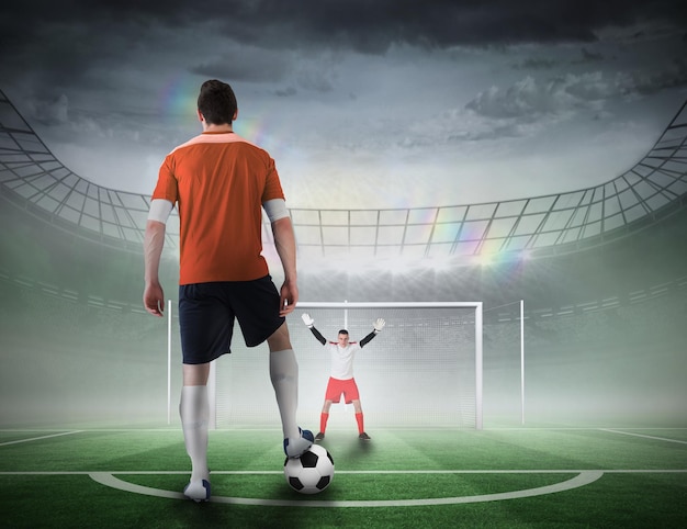 Imagen compuesta de jugador de fútbol a punto de ejecutar un penalti contra un campo de fútbol en un estadio grande