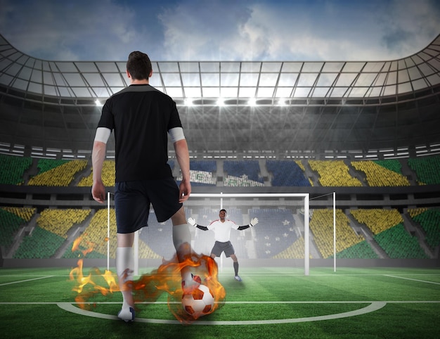 Imagen compuesta de jugador de fútbol a punto de ejecutar un penalti contra un campo de fútbol en un estadio grande